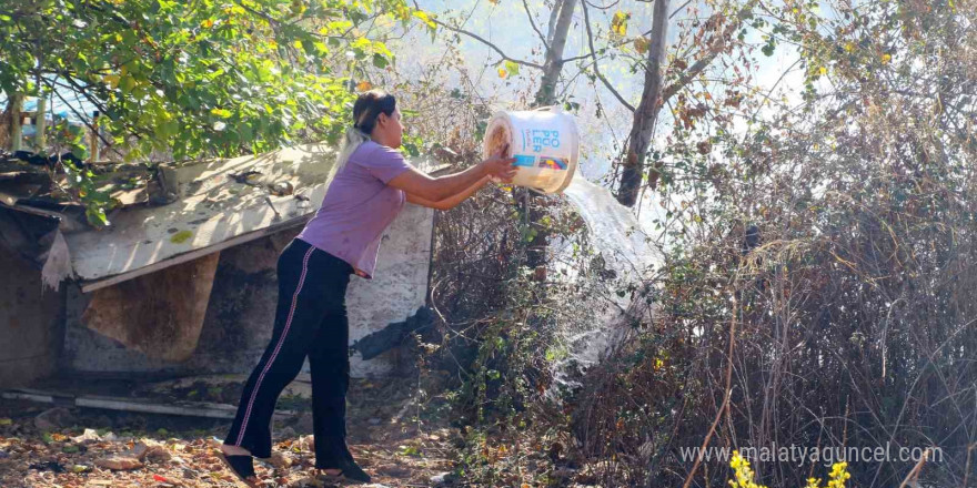 Evinin etrafını saran alevlere gözyaşları içinde hortumla müdahale etti